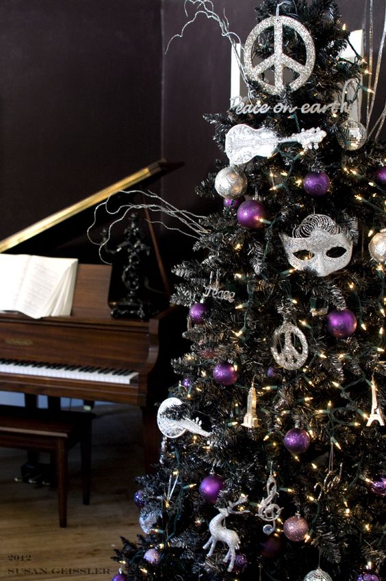 a black tree with whimsy decor and silver and purple ornaments