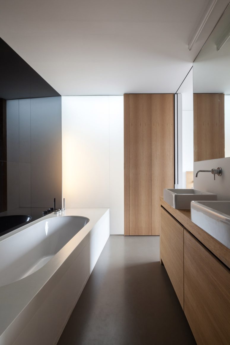 The bathroom features warm wood panels, sleek black and white walls and a modern bathtub