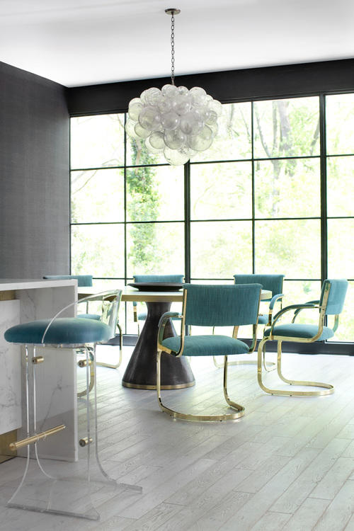 The dining area is located by the window, and the upholstered gilded chairs echo with the lucite ones The dining area is located by the window, and the upholstered gilded chairs echo with the lucite ones