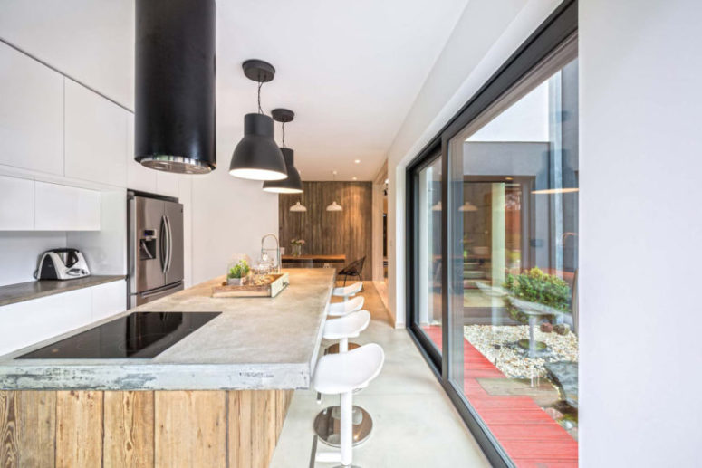 industrial kitchen The kitchen is modern, with a rough wood and concrete kitchen island and modern hanging lamps