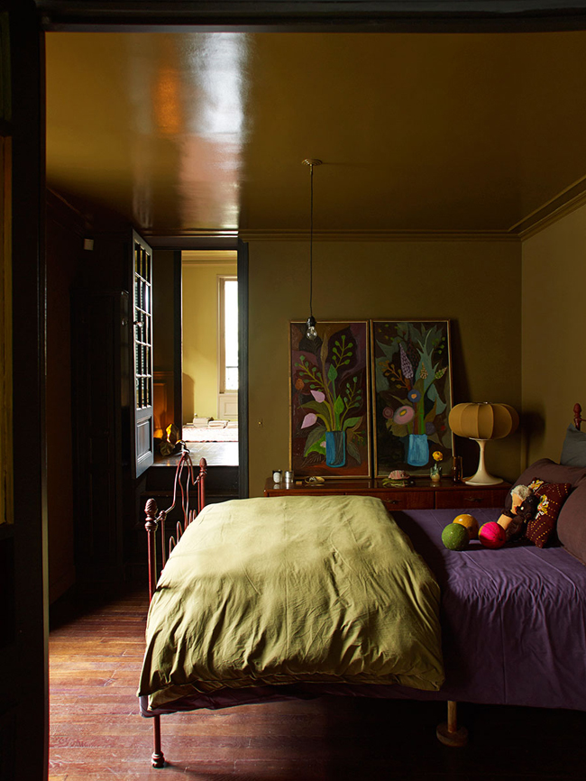 The master bedroom is done in ocher and spruced up with bold artworks from the owners' collection