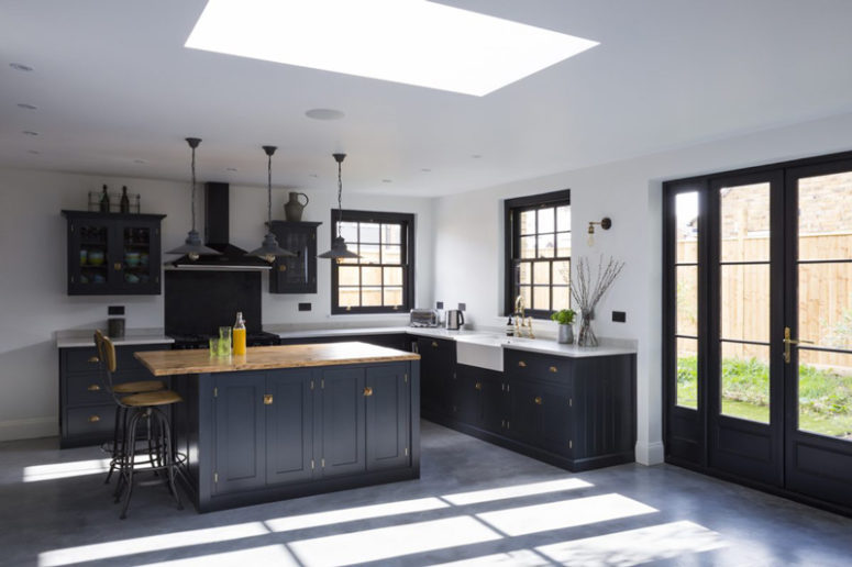 The spacious kitchen is done in light colors, and the cabinetry is dark and vintage, with brass details and wooden countertops The spacious kitchen is done in light colors, and the cabinetry is dark and vintage, with brass details and wooden countertops