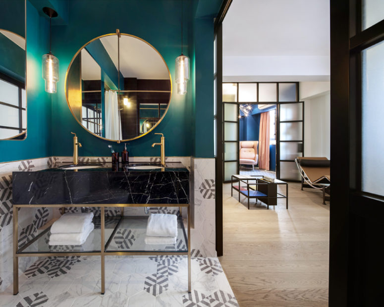 I love the contrast between an emerald wall and a black marble countertop with brass faucets and framing