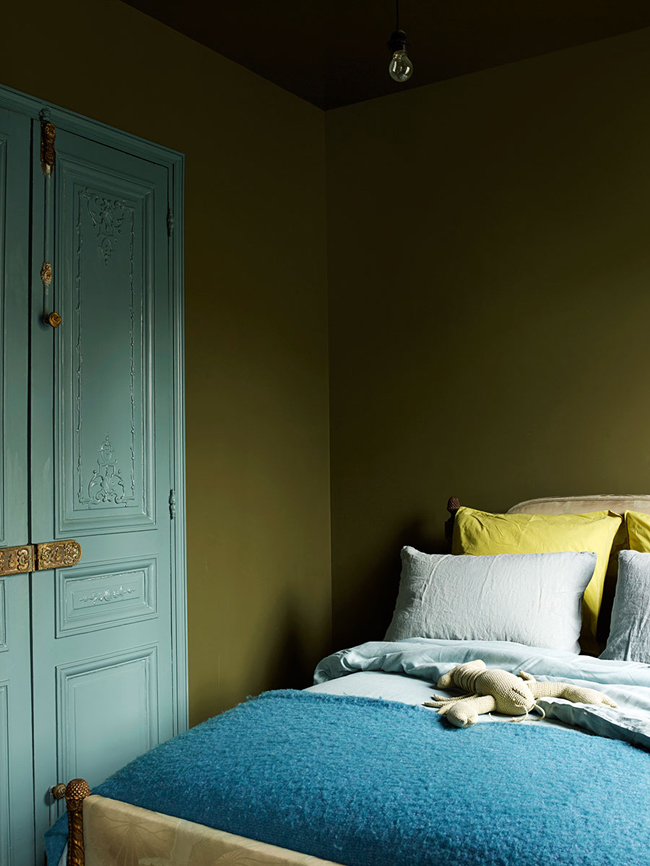 moody bedroom The guest bedroom is decorated in the same moody shade of green as the living room, and there are blue touches added