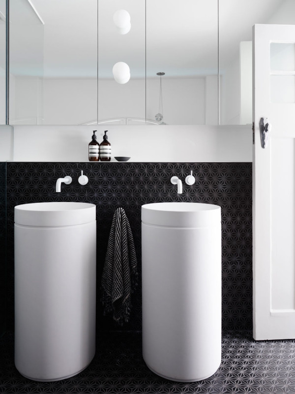 The white free-standing sinks look outstanding in front of charcoal geometric tiles