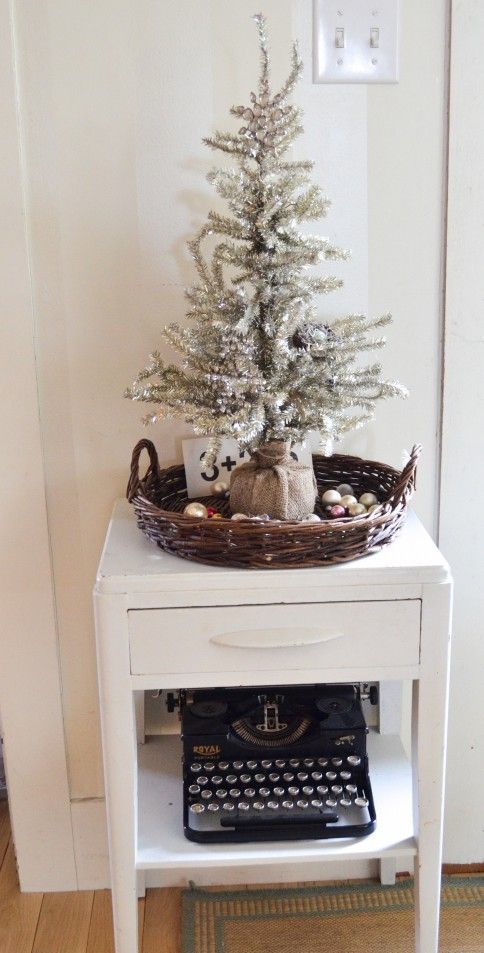 a silver tree wrapped with burlap, placed into a basket with ornaments