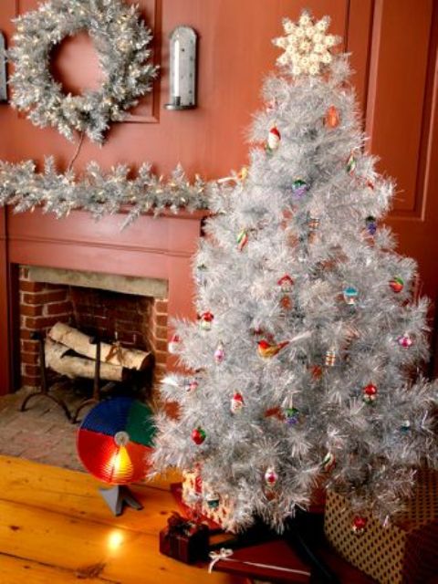 a silver tree decorated with colorful vintage ornaments, a silver and wreath with lights