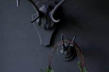 10 black antlers and a small twig wreath with evergreens and pinecones