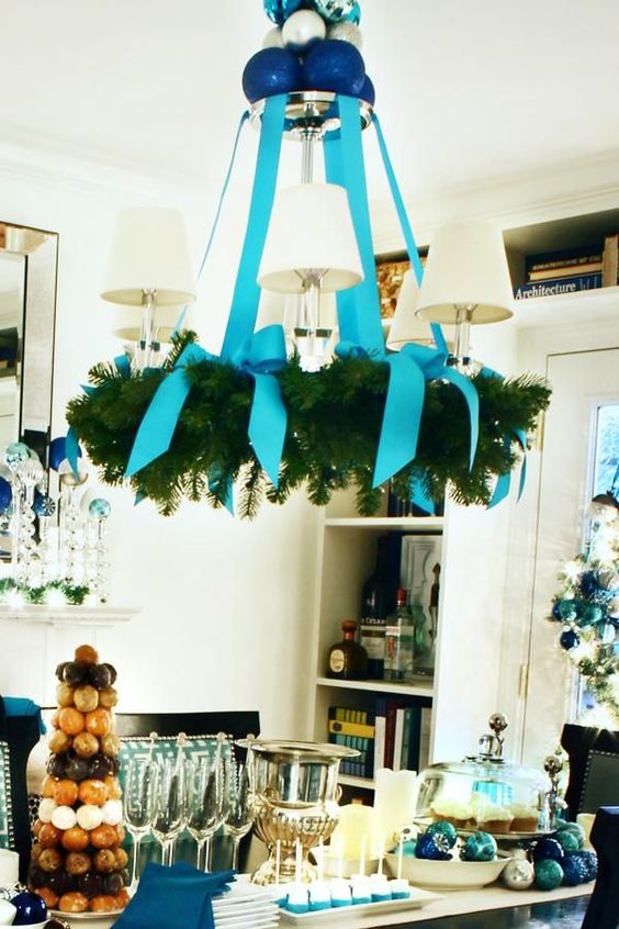 a usual chandelier covered with an evergreen wreath and turquouse ribbon