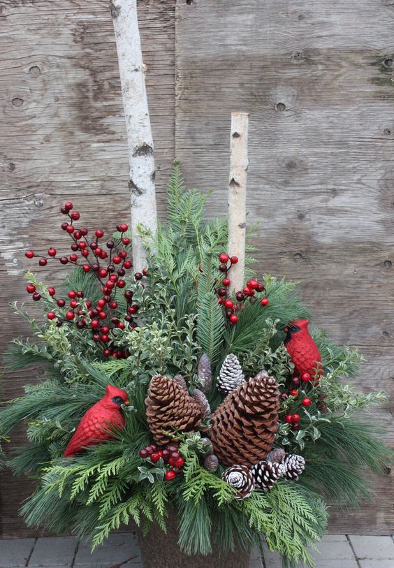 winter urn arrangement with pinecones, red berries and cardinals