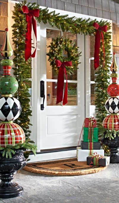 whimsy porch decor with evergreen garlands, lights, large ornament topiaries and gift boxes