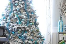 14 turquoise ornaments and garlands on a flocked Christmas tree