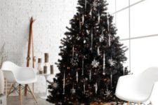 17 a lush black tree wwith white and silver snowflake ornaments and lights