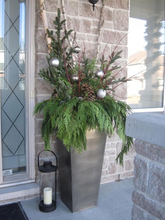 a metal urn with evergreens, pinecones and ornaments
