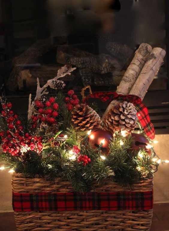 a basket with evergreens, berries, pinecones and lights