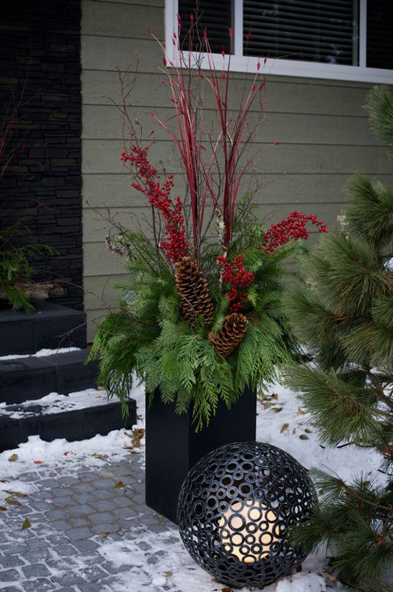 a modern black urn, foliage, pinecones, berries and red branches