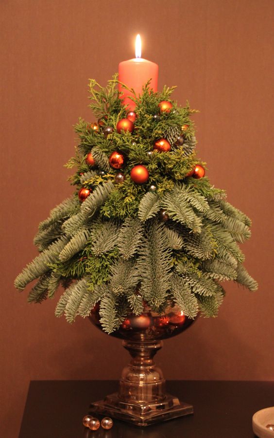 a simple small arrangement with a candles, evergreens and tiny copper ornaments