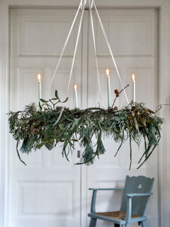 a Christmas chandelier of greenery and evergreens, twigs and candles is a beautiful and all-natural holiday decor idea