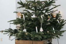 a Nordic Christmas tree with lights, porcelain and wooden ornaments and with old crates cover the tree base