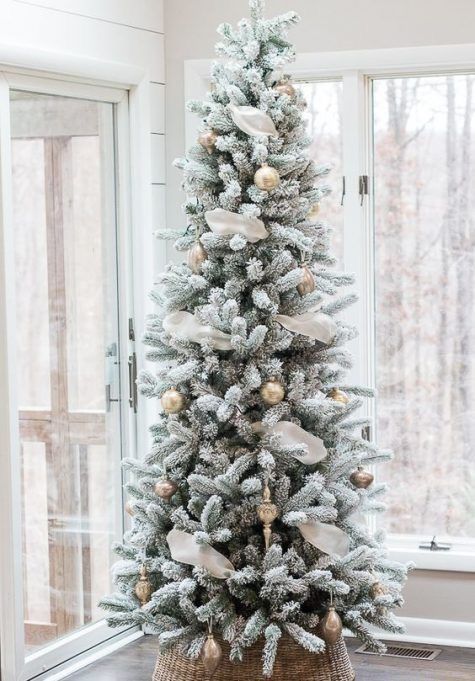 a catchy flocked Christmas tree with white ribbon and gold ornaments plus a basket base cover is a stylish idea
