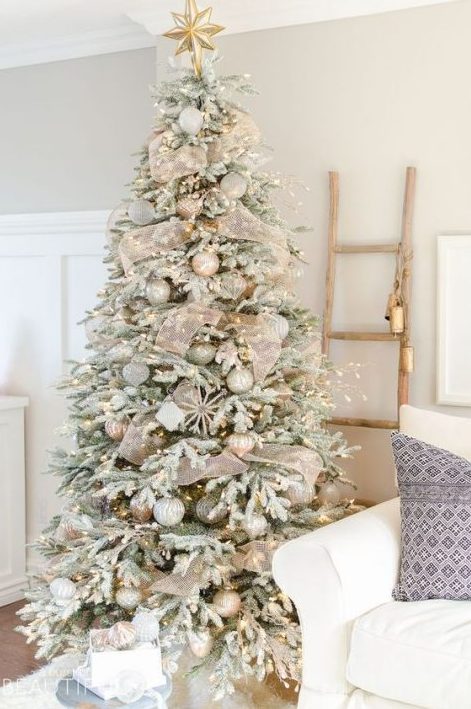 a flocked Christmas tree with lights, metallic ornaments, snowflakes and shiny mesh ribbons looks festive