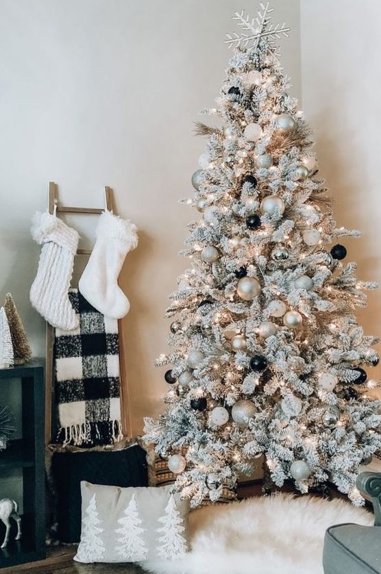 a flocked Christmas tree with lights, white, metallic and black ornaments and a silver star on top is amazing
