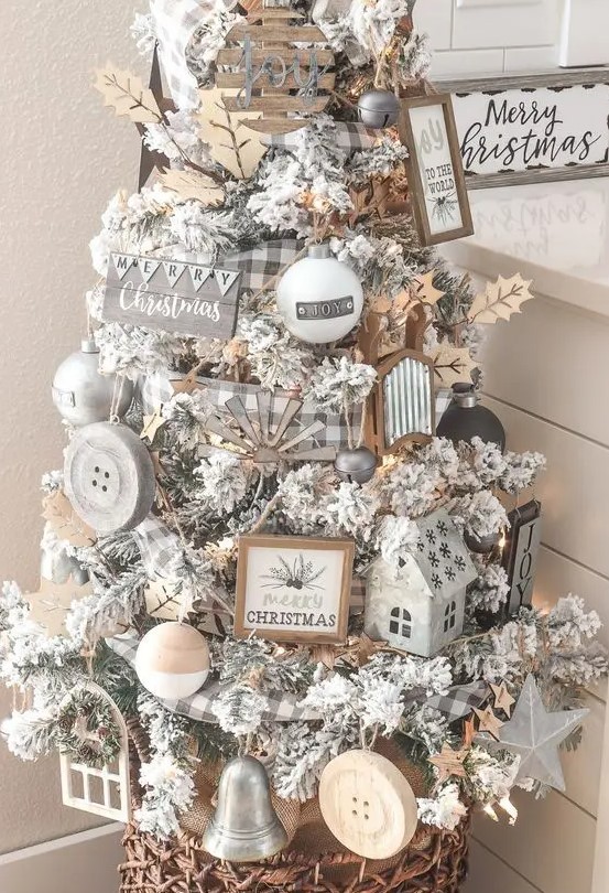 a flocked Christmas tree with wooden ornaments, buffalo check ribbon, lights and leaves for a farmhouse space