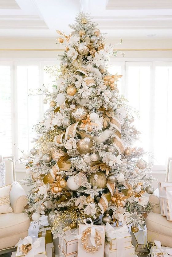 a glam flocked Christmas tree with oversized metallic ornaments, ribbons, branches and some faux blooms is amazing