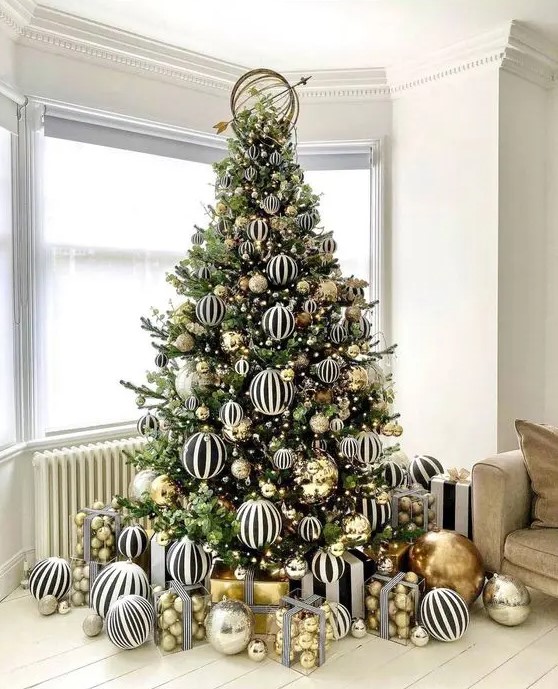 a jaw-dropping modern Christmas tree decorated with black and white striped and gold large-scale ornaments is amazing