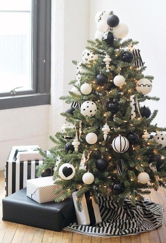 a lovely Christmas tree with black and white ornaments including polka dot ones, with lights and polka dot ribbons plus a striped tree skirt