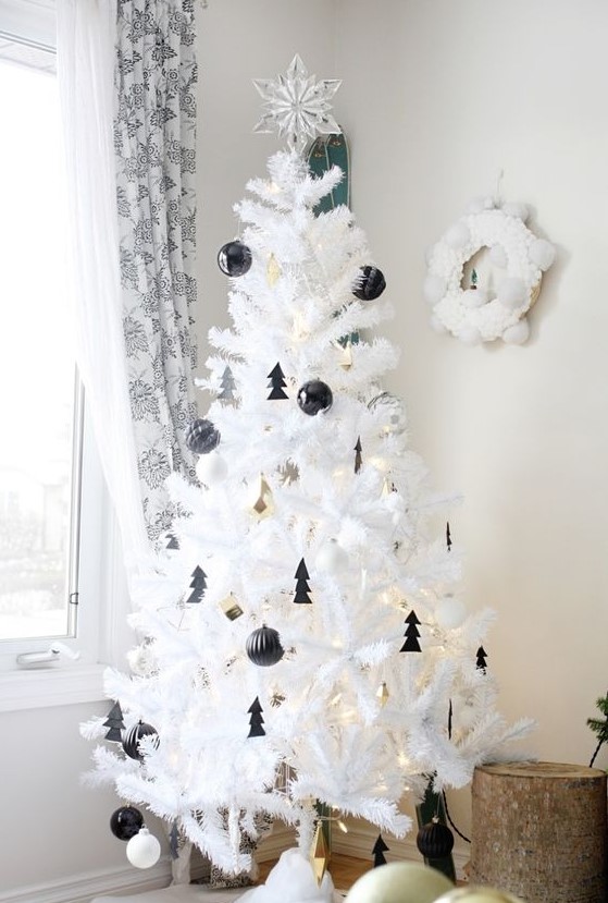 a lovely white Christmas tree decorated with black baubles and little Christmas trees, with gold bells and lights is amazing