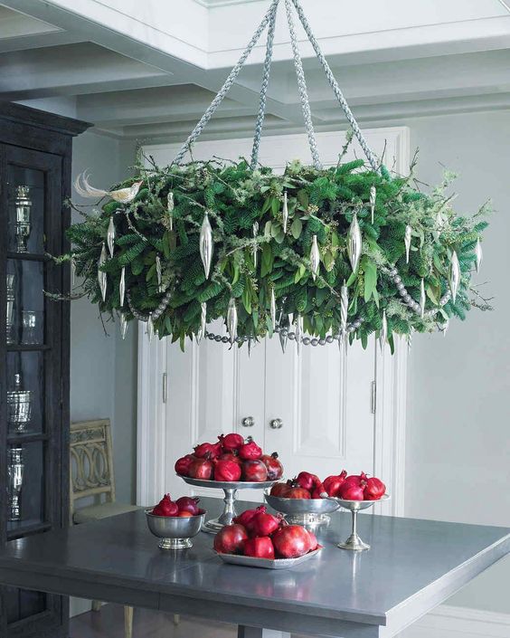 a lush and glam Christmas chandelier of lots of greenery and evergreens and silver icicle ornaments is absolutely adorable