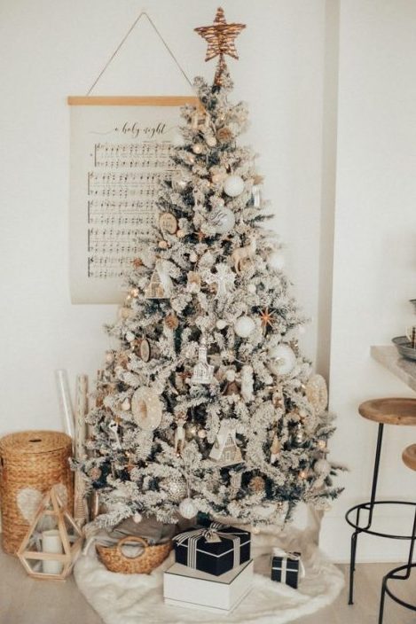 a magical flocked Christmas tree with white balls, whimsy and shiny ornaments, bells and little house ornaments