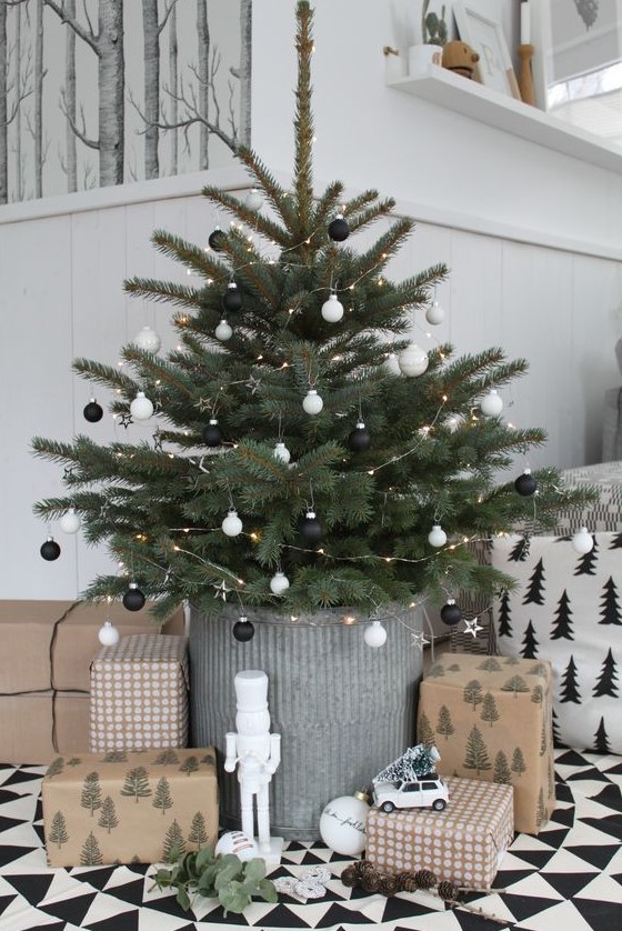 a minimalist Scandi Christmas tree placed into a planter, with small black and white ornaments and LED lights