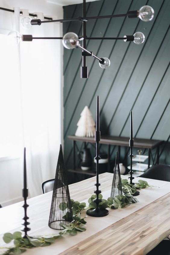 a modern Christmas tablescape with greenery, black candleholders and black cone trees is cool