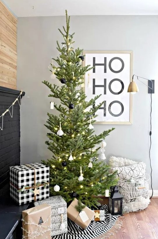 a modern Christmas tree with white and black ornaments and lights is a stylish idea that will fit a Scandinavian space, too