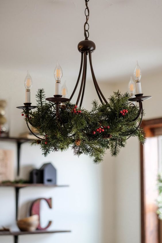 a vintage chandelier with evergreens and berries is a stylish solution for a farmhouse space during the holidays
