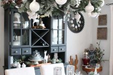 a vintage-inspried chandelier with flocked evergreens, pinecones and white ornaments is a stylish farmhouse Christmas decor idea