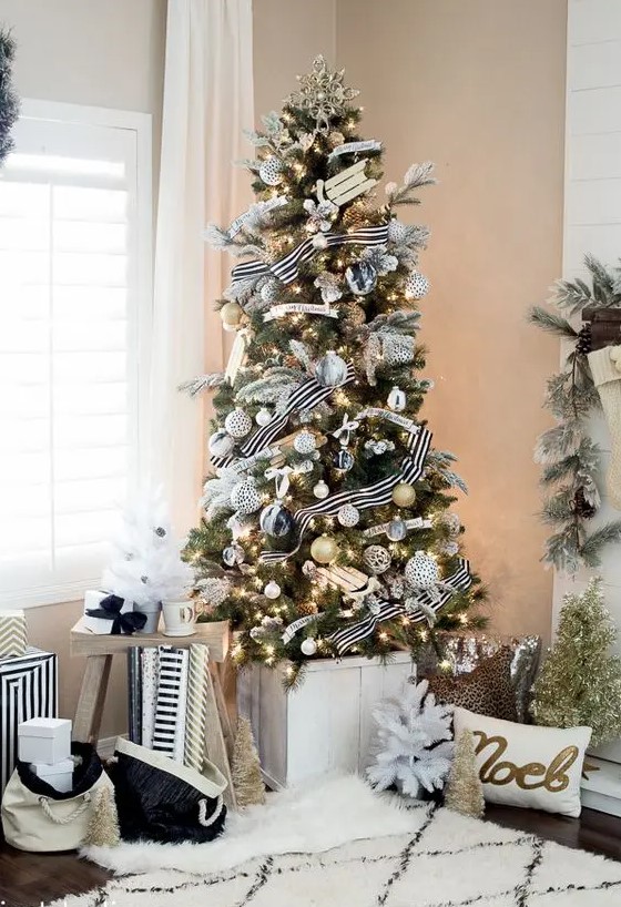 an exquisite Christmas tree with black, white and gold ornaments and cool striped ribbons and lights plus a gold snowflake topper