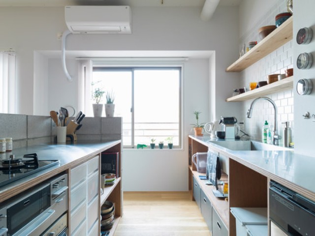 The kitchen is minimalist, with white and warm wood sleek surfaces