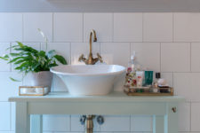 09 The bathroom counter is mint-colored, and gold touches make the space more refined