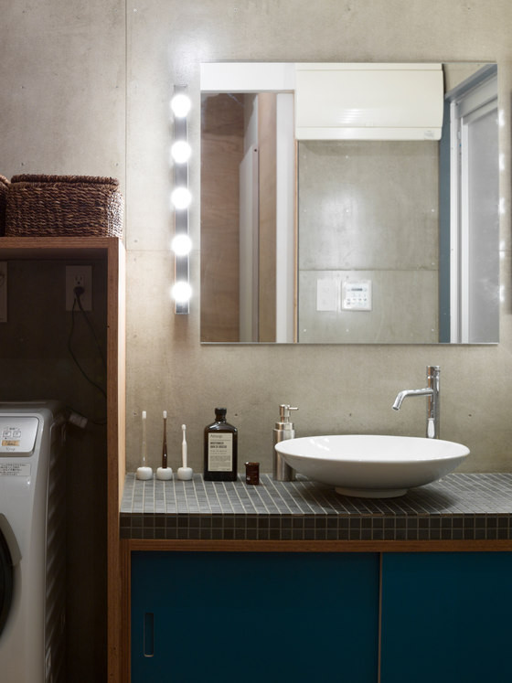 The bathroom is done in concrete, small tiles and blue shades