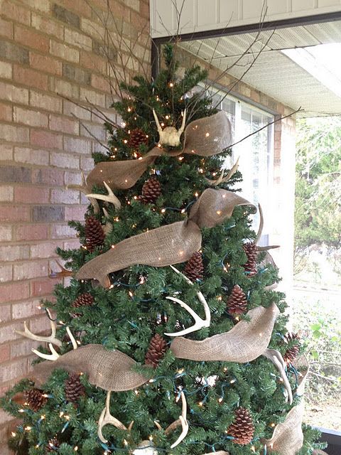 a large tree with pinecones, lightsm antlers and burlap deco mesh