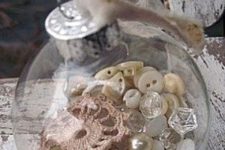 16 a transparent glass ornament filled with buttons, pearls and lace