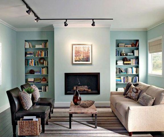 track lights accentuate a faux fireplace and artworks