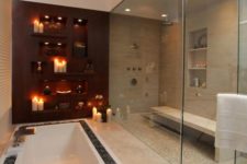 23 a large steam room with a bench opens to a sunken bathtub with stone lining