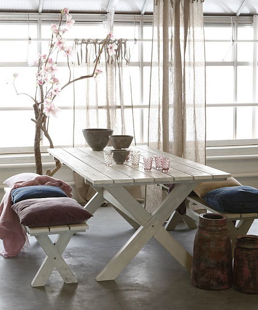 relaxed boho feel dining space with a whitewashed table and benches, colorful pillows