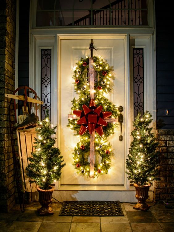 lit up evergreen wreaths trio with ornaments and ribbon