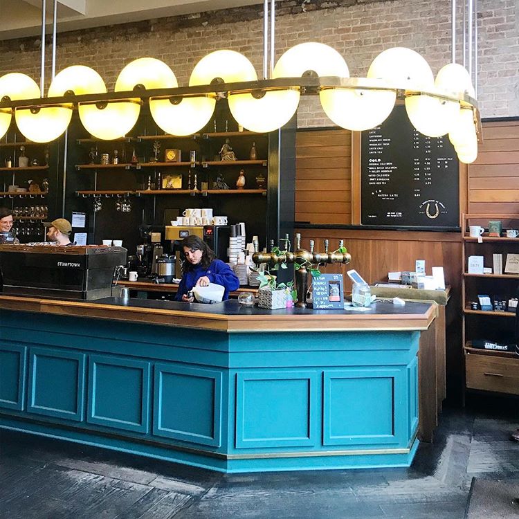 creative lighting fixture around a coffee bar not only light the space up but also makes a statement (via @coffeeshopinteriors)
