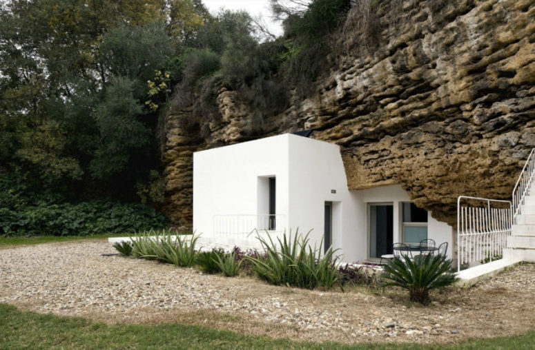 White plaster house architecture looks spotless next to discolored rock and there's a lot of greenery around White plaster house architecture looks spotless next to discolored rock and there's a lot of greenery around